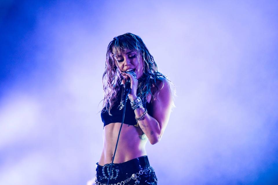 Miley Cyrus performs on stage in a crop top