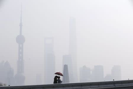 Women walk on a bridge in front of the financial district of Pudong amid heavy smog in Shanghai, China, December 15, 2015. REUTERS/Aly Song