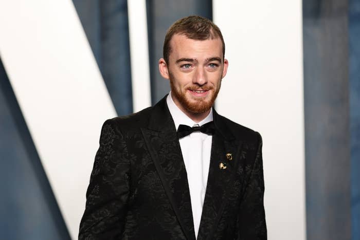 Angus Cloud in a patterned tuxedo with bow tie and lapel pin, posing for the camera on the red carpet