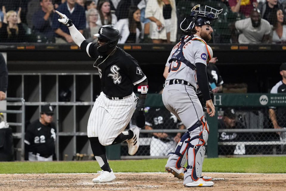 Chicago White Sox's Josh Harrison, left, celebrates as he scores on a two-run single by Andrew Vaughn as Detroit Tigers catcher Eric Haase looks to the field during the seventh inning of a baseball game in Chicago, Friday, Aug. 12, 2022. (AP Photo/Nam Y. Huh)