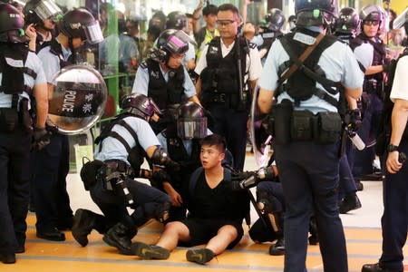 A protester is detained by the police officers at Amoy Plaza shopping mall in Kowloon Bay, Hong Kong