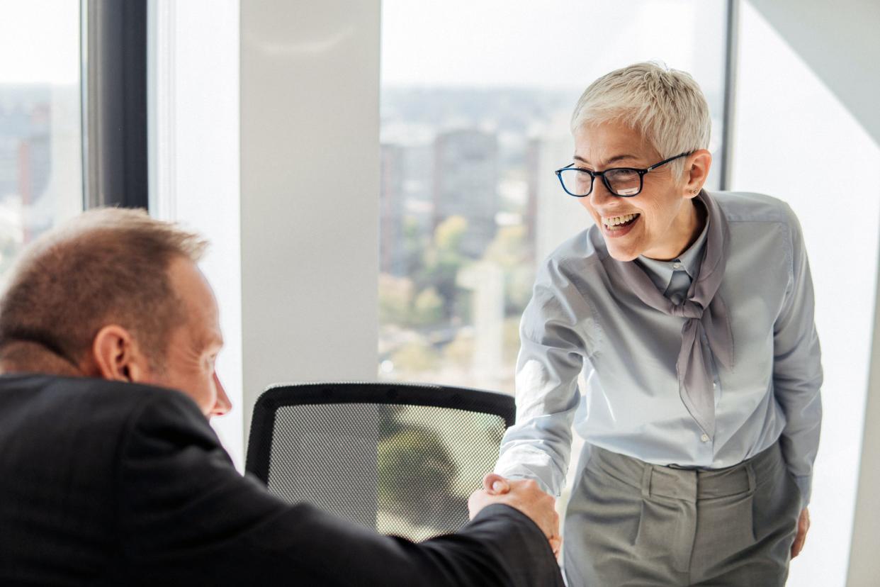 senior woman shaking hands standing up from chair