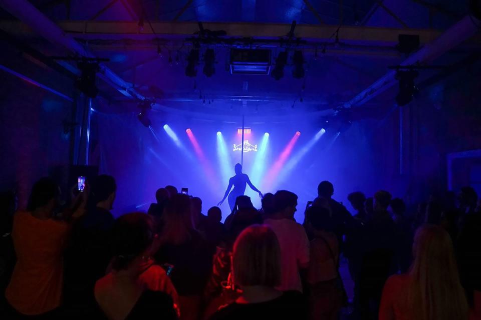 The silhouette of a dancer on a foggy stage with a crowd looking on.