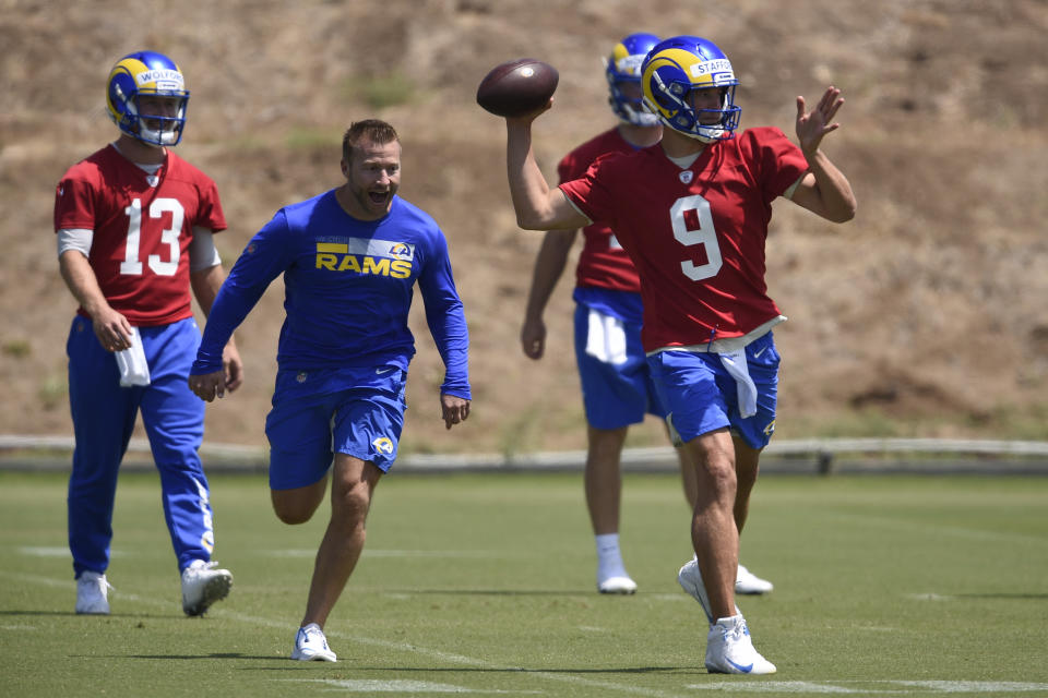 Los Angeles Rams' Matthew Stafford, right, runs a drill while pursued by head coach Sean McVay, center, as John Wolford watches during NFL football practice in Thousand Oaks, Calif., Thursday, May 27, 2021. (AP Photo/Kelvin Kuo)