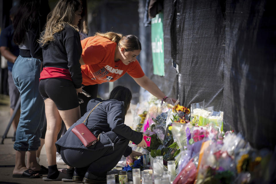 Stacey Sarmiento coloca unas flores el domingo 7 de noviembre de 2021 en un monumento conmemorativo improvisado en honor de la gente que falleció en el festival de música Astroworld, en Houston. Su amiga Rudy Peña murió en el evento del viernes. (AP Foto/Robert Bumsted)