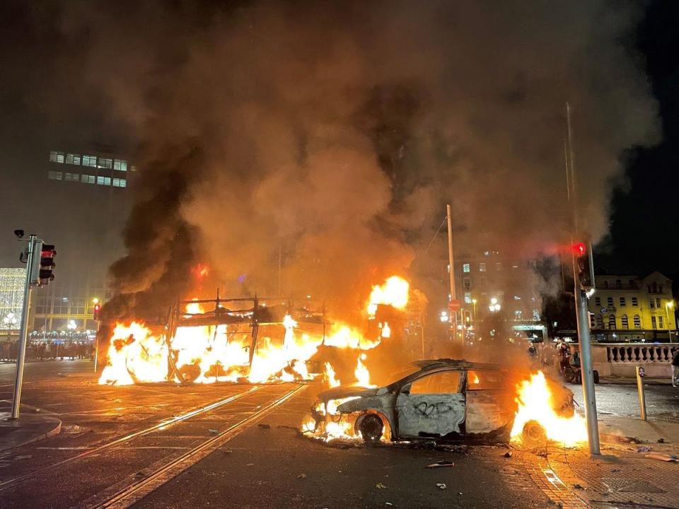 A bus and car on fire on O’Connell Street in Dublin city centre (PA)