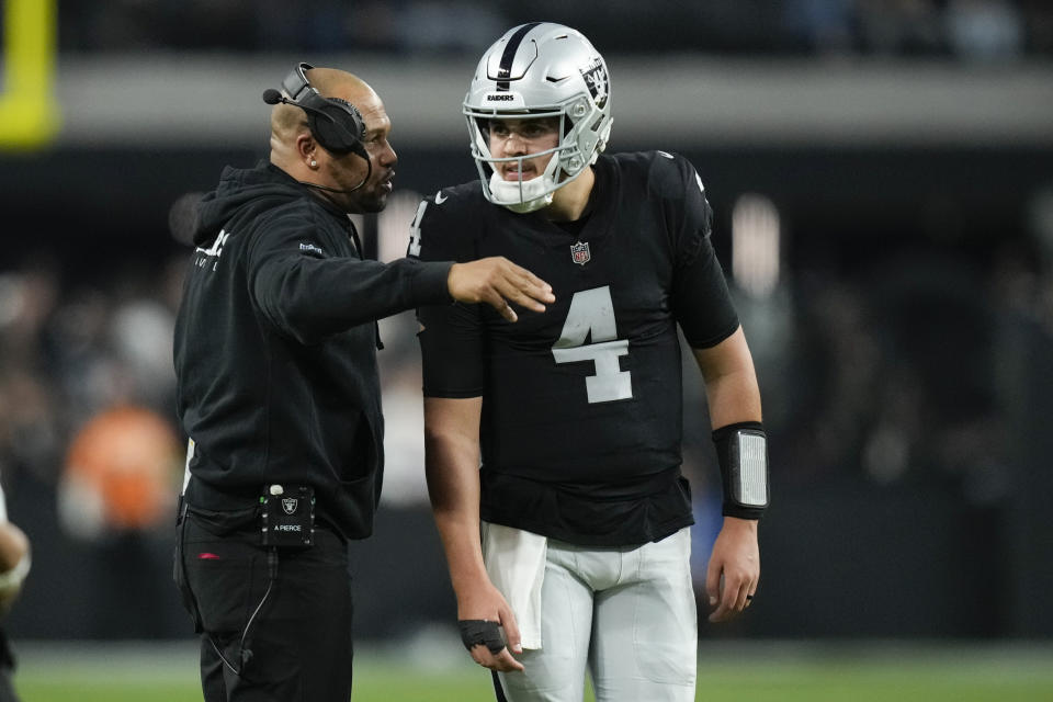 Las Vegas Raiders quarterback Aidan O'Connell (4) talks to interim head coach Antonio Pierce during the second half of an NFL football game against the Denver Broncos, Sunday, Jan. 7, 2024 in Las Vegas. (AP Photo/John Locher)