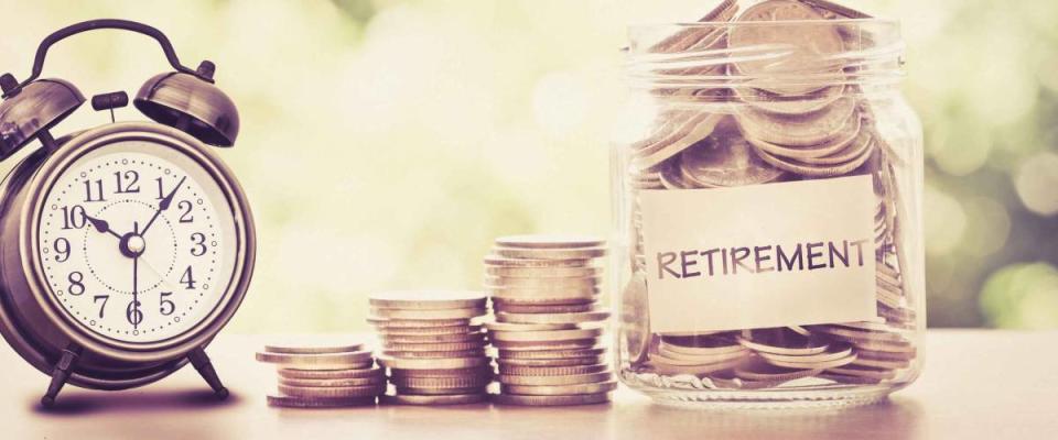 Hand putting Coins in glass jar with retro alarm clock  for time to money saving for retirement concept , vintage retro color tone