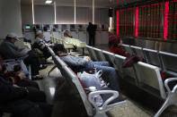 A man takes a nap as investors monitor stock prices at a brokerage house in Beijing, Friday, Dec. 6, 2019. Shares swung higher in Asia on Friday after a wobbly day of trading on Wall Street as investors awaited a U.S. government jobs report and kept an eye out for developments in China-U.S. trade talks. (AP Photo/Andy Wong)