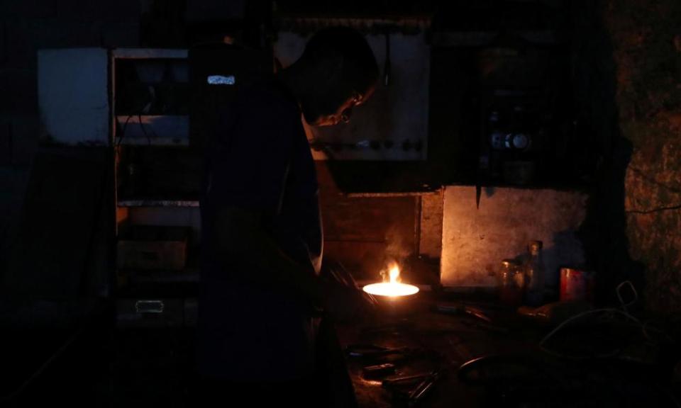 A man works inside a mechanical workshop during the blackout in Caracas on Friday.