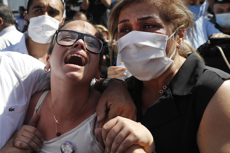 The sister of Najib Hetti, left, one of the ten firefighters who were killed during the Aug. 4 explosion that hit the seaport of Beirut, mourns during his funeral at the firefighter headquarters, in Beirut, Lebanon, Monday, Aug. 17, 2020. (AP Photo/Hussein Malla)