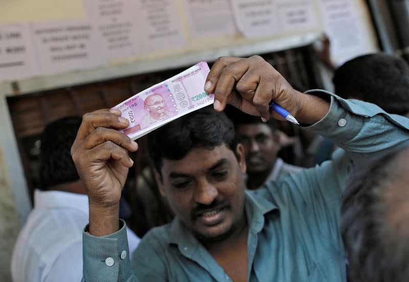 FILE PHOTO: A man holds 2000 Indian rupees notes as he gets out of a bank in Mumbai