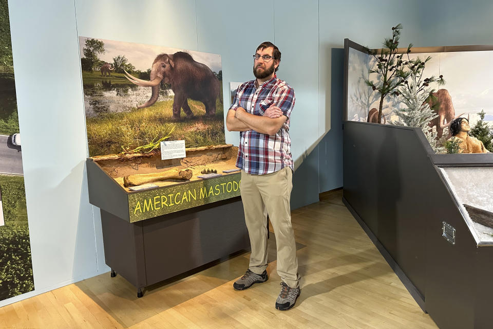 Cory Redman, science curator at the Grand Rapids Public Museum, stands near a mastodon display at the museum on Thursday, May 18, 2023, in Grand Rapids, Mich. Mastodon bones being shown at GRPM were unearthed last year during a drainage dig in western Michigan and belonged to a juvenile mastodon that lived 13,000 years ago. (AP Photo/Mike Householder)