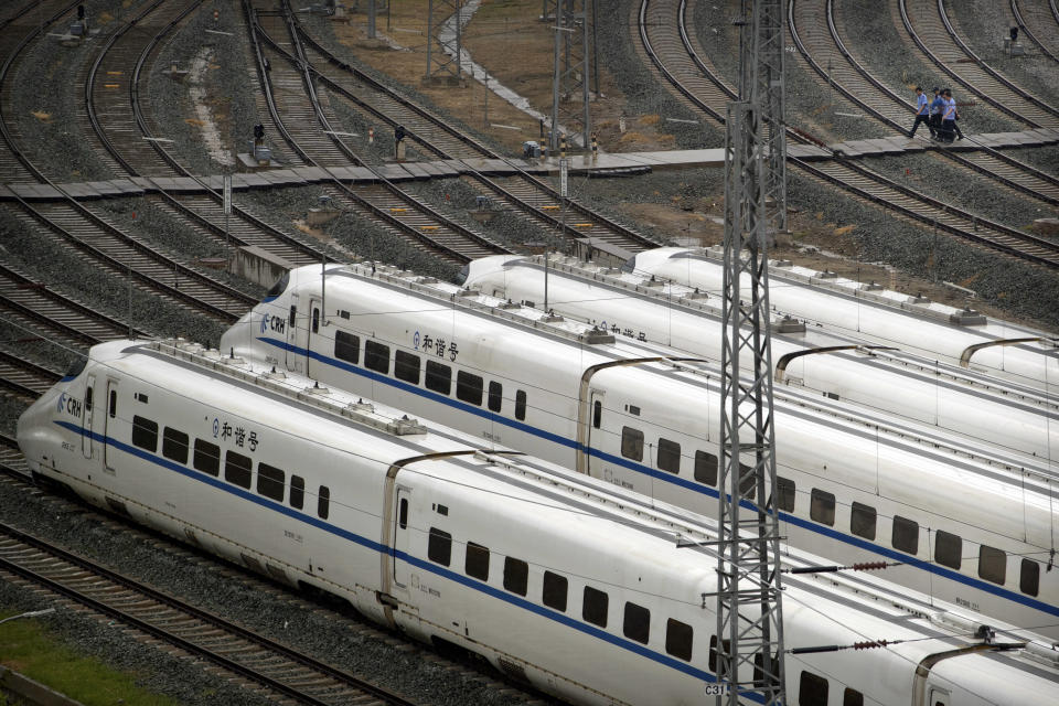 In this Aug. 30, 2018, file photo, workers walk past parked high-speed trains at a maintenance yard during a media tour ahead of the 2018 Forum on China-Africa Cooperation in Beijing. Chinese funds for infrastructure and investment projects like railroads have flooded into Africa in recent years, prompting warnings from the United States that the money comes with strings attached. (AP Photo/Mark Schiefelbein, File)