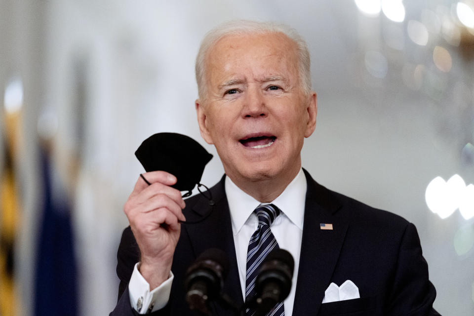 FILE - In this March 11, 2021, file photo President Joe Biden holds up his mask as he speaks about the COVID-19 pandemic during a prime-time address from the East Room of the White House in Washington. Biden spent his first 100 days in office encouraging Americans to mask up and stay home to slow the spread of the coronavirus. His task for the next 100 days will be to lay out the path back to normal. (AP Photo/Andrew Harnik, File)