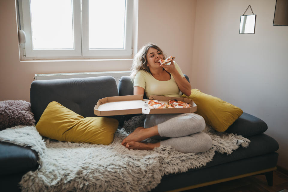 Frau isst Pizza auf der Couch