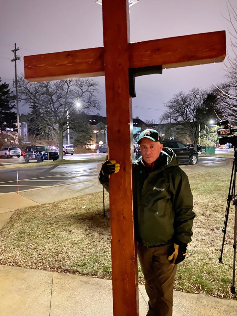 Dan Beazley, of Northville, holds a 10-foot cross he made about a year and a half ago and has driven or carried to tragedies across the country, including Oxford High School, Uvalde, Texas, and the Memphis funeral for Tyre Nichols. He said this one felt close to home, he has a daughter who attended MSU and he roots for their teams. "But this isn't about sports, this is about the light of the world," he said, standing outside of Eastminster Presbyterian Church in East Lansing during an evening rain on Feb. 14, 2023.