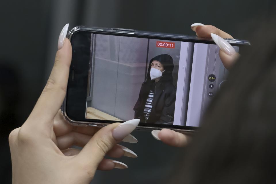 A journalist films as Radio Free Europe-Radio Liberty editor Alsu Kurmasheva sits in a glass cage in a courtroom in Kazan, Russia, Monday, Oct. 23, 2023. A Russian court on Monday ordered a Russian-American journalist who was detained last week on charges of failing to register as a foreign agent to remain in custody until early December, her employer reported. (AP Photo/Vladislav Mikhnevskii)