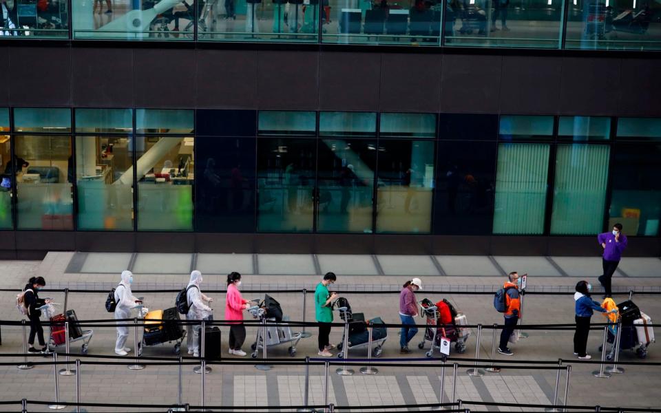 Passengers wearing PPE (personal protective equipment) queue up to board a China bound flight at Terminal 2 of Heathrow airport - AFP