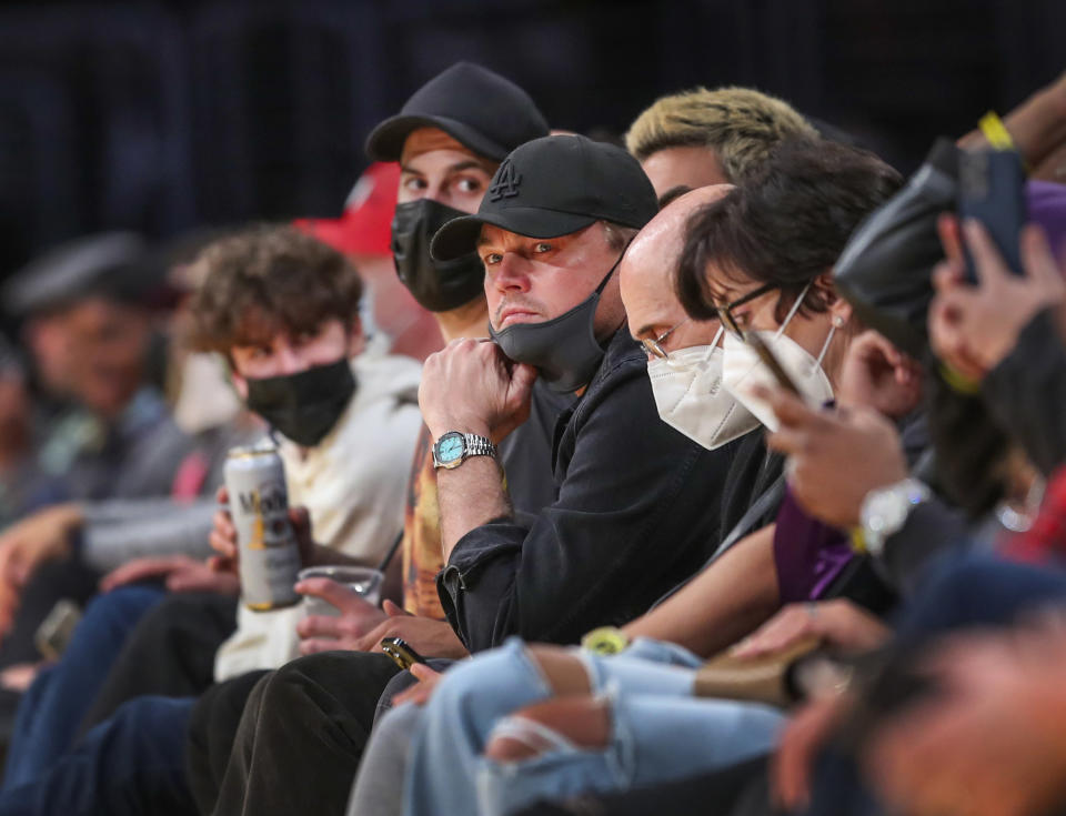 Sitting and wearing a cap with his mask below his mouth