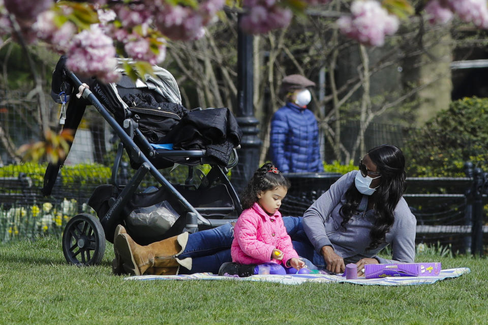 People wear masks while enjoying Washington Square Park Tuesday, April 21, 2020, in New York. (AP Photo/Frank Franklin II)