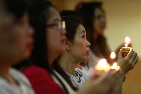 Malaysian women hold candles during a special prayer for passengers onboard the missing Malaysia Airlines Flight MH370 at Chinese Assembly Hall in Kuala Lumpur March 19, 2014. REUTERS/Samsul Said