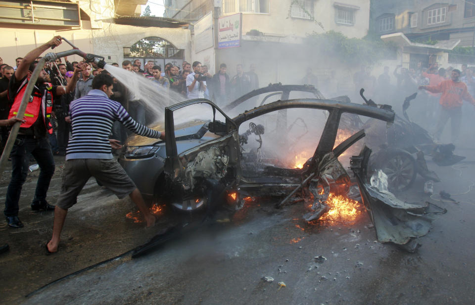 FILE - People gather around a wreckage of the car in which was killed Ahmed Jabari, head of the Hamas military wing in Gaza City, Wednesday, Nov. 14, 2012. Prime Minister Benjamin Netanyahu and other Israeli leaders have repeatedly threatened to kill Hamas leaders following the group's deadly Oct. 7, 2023 cross-border attack that sparked the war in Gaza. Israel has a long history of assassinating its enemies, many carried out with precision airstrikes. (AP Photo/Adel Hana, File)