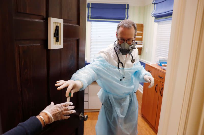 Dr Greg Gulbransen hands a test for the coronavirus disease (COVID-19) after taking a nasal swab from a toddler while maintaining visits with both his regular patients and those confirmed to have the virus at his pediatric practice in Oyster Bay, New York