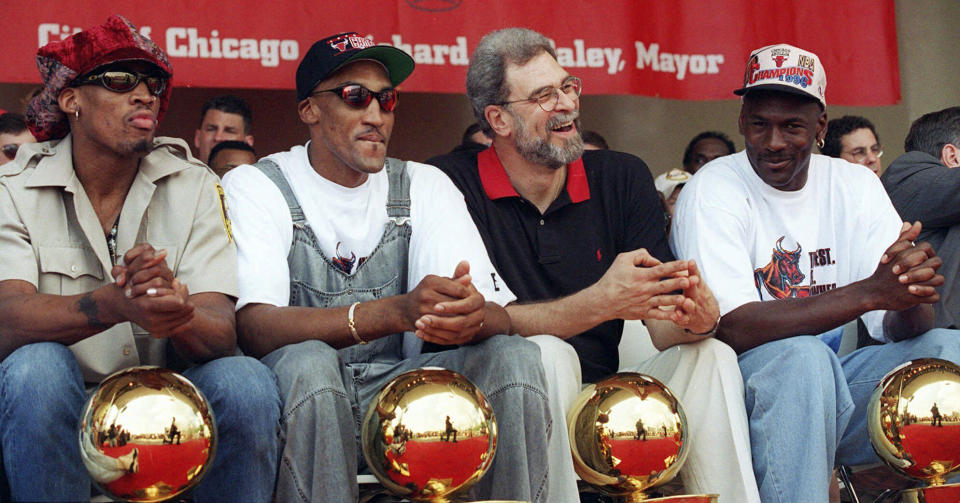 FILE - Chicago Bulls, from left: Dennis Rodman, Scottie Pippen, coach Phil Jackson, and Michael Jordan, sit with four NBA trophies at their feet during a championship celebration on June 18, 1996, in Chicago's Grant Park. Jordan, Pippen and Rodman are the headliners for the inaugural class for the Chicago Bulls' Ring of Honor. The Bulls unveiled their plans for the Ring of Honor on Tuesday, Dec. 12, 2023. (AP Photo/ Beth A. Keiser, File)