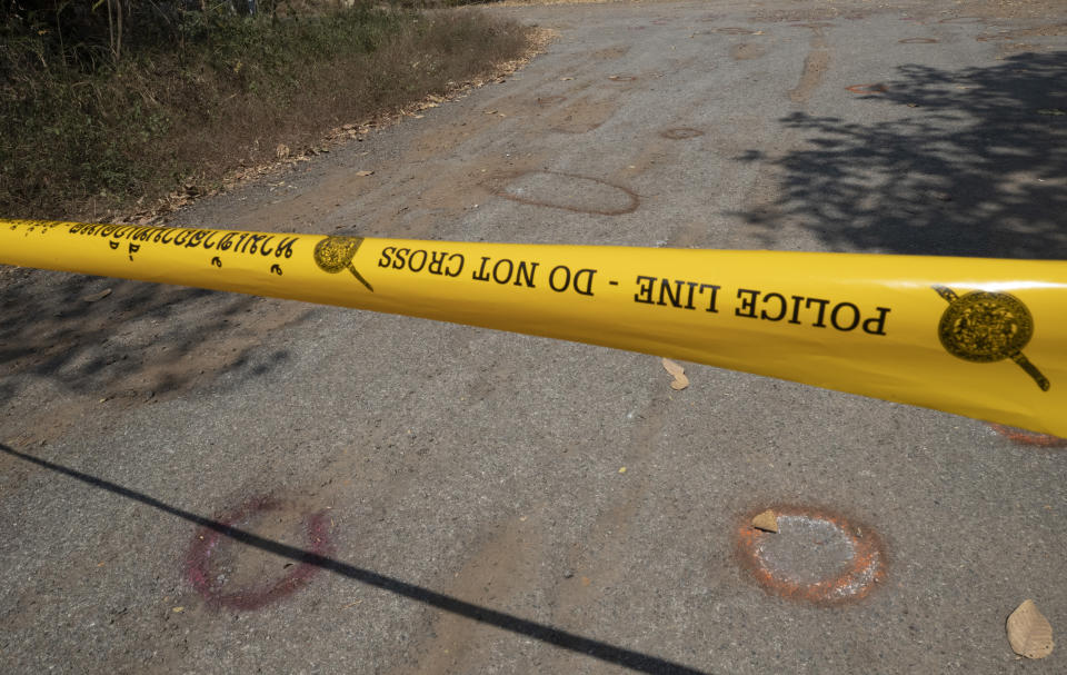 Red circles mark where bullet casings evidence were found behind police tape at the scene of the weekend's mass shooting at the weekend's mass shooting that partially took place at the Wat Pa Sattharuam temple, Tuesday, Feb. 11, 2020, in Nakhon Ratchasima, Thailand. A rogue Thai soldier whose rampage left 29 people dead and dozens more injured terrorized a Buddhist temple complex in rural northeastern Nakhon Ratchasima province on his way to a shopping mall, where he held shoppers hostage in a nearly 16-hour siege. (AP Photo/Sakchai Lalit)