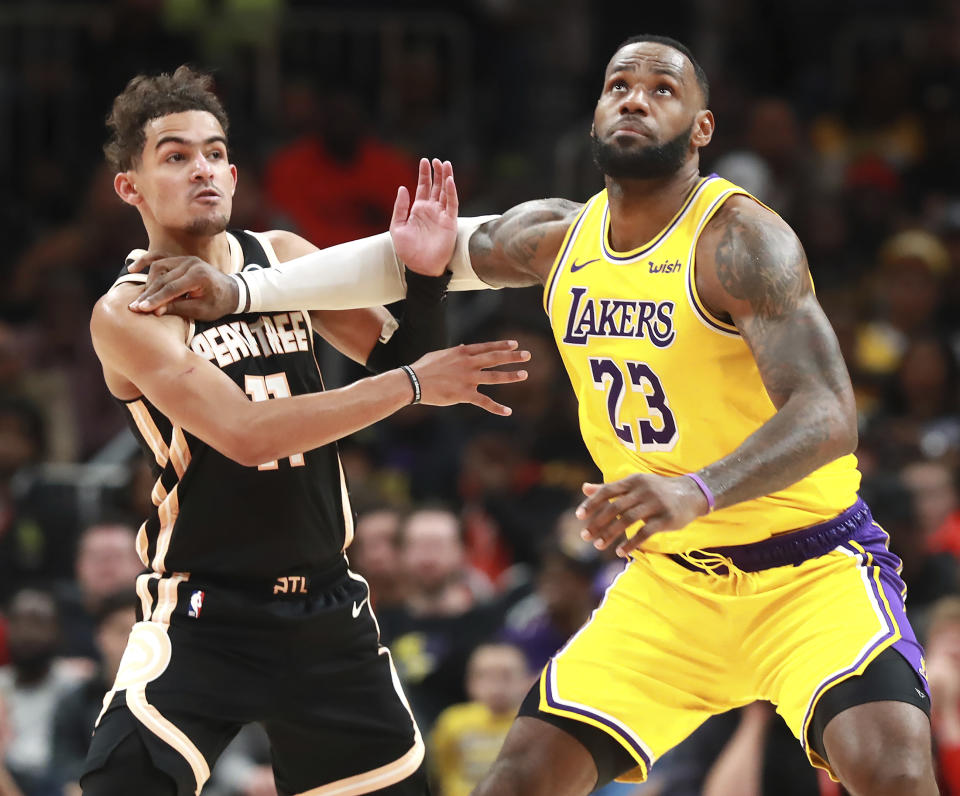 Los Angeles Lakers forward LeBron James, right, pushes Atlanta Hawks guard Trae Young out of the way as he prepares to grab a jump ball during the second half of an NBA basketball game Sunday, Dec. 15, 2019, in Atlanta. (Curtis Compton/Atlanta Journal-Constitution via AP)