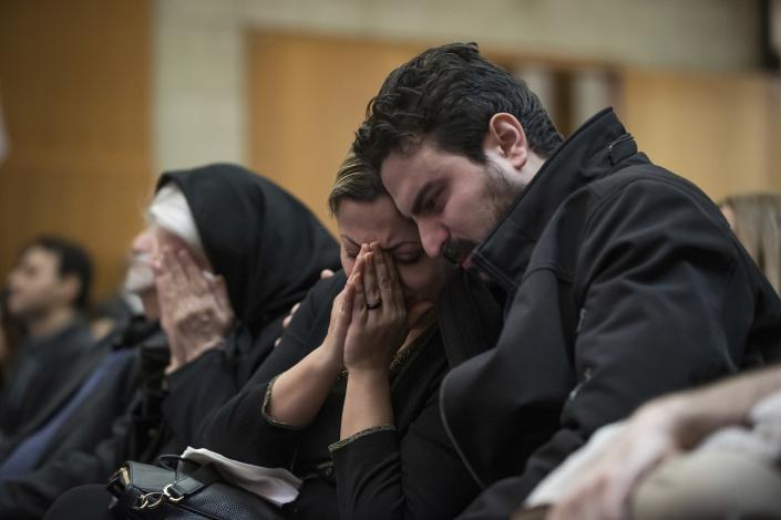 FILE - In this Jan. 19, 2020 file photo, Babak Razzaghi, right, consoles his sister Banafsheh Razzaghi as they mourn the loss of their sister Niloofar Razzaghi, brother-in-law Ardalan Hamidi and nephew Kamyar Hamidi, who died in a Ukraine airplane crash in Iran on Jan. 8, 2020, during a vigil, at the Har El synagogue in West Vancouver, British Columbia. More questions than answers remain about the disaster that killed 176 people on board the Ukrainian jetliner, a year after Iran’s military mistakenly downed the plane with surface-to-air missiles. Officials in Canada, which was home to many of the passengers on the doomed plane, and other affected countries have raised concerns about the lack of transparency and accountability in Iran’s investigation of its own military. (Darryl Dyck/The Canadian Press via AP, File)