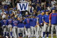 Chicago Cubs fans hold a giant "W" sign over the Chicago Cubs as they leave the field while Cubs manager David Ross, center left, and others greet Cubs shortstop Javier Baez (9) after the team defeated the New York Mets in a baseball game, Thursday, June 17, 2021, in New York. (AP Photo/Kathy Willens)