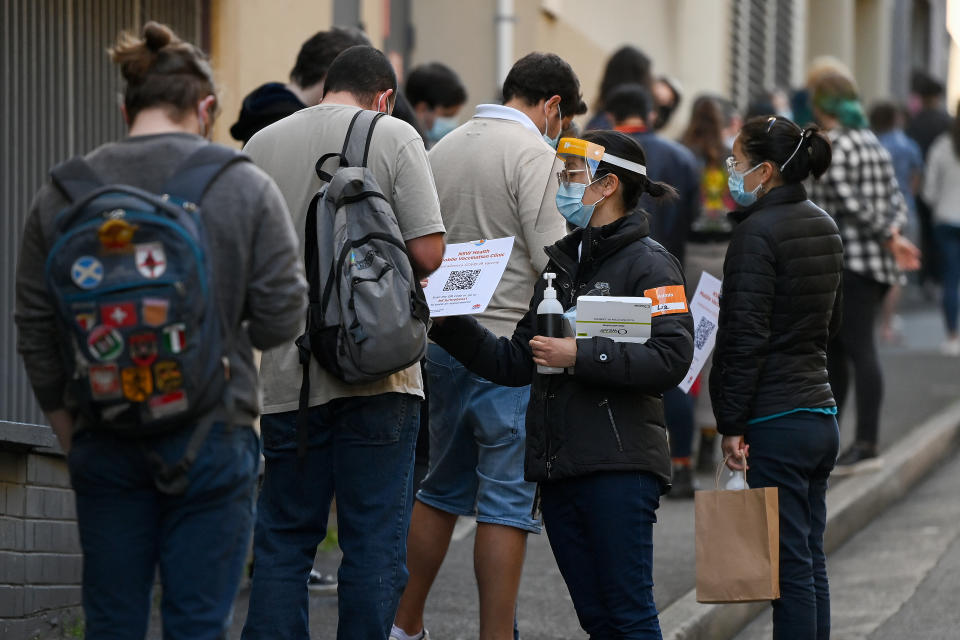 NSW Health workers wear Personal Protection Equipment (PPE) as they get people to sign in at the NSW Health Walk-in AstraZeneca vaccination clinic in Glebe. Source: AAP