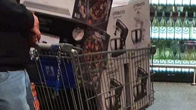 Photo of man in Aldi with six Special Buy Stand Mixers in Trolley, man facing away from camera close image of hand and leg visible