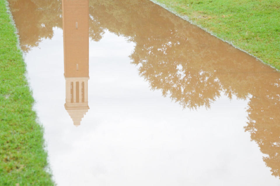 The Denny Chimes at the University of Alabama, a tall tower reflected in a pond of water.