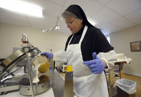 Sister Rebecca Leis pours low-gluten alter bread batter into a machine that bakes the thin bread at the Benedictine Sisters of Perpetual Adoration monastery in Clyde, Missouri, December 18, 2014. REUTERS/Dave Kaup