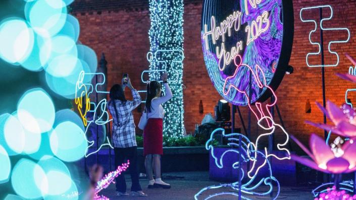 People take photos with their mobile phones in front of &quot;Happy New Year 2023&quot; light illuminations