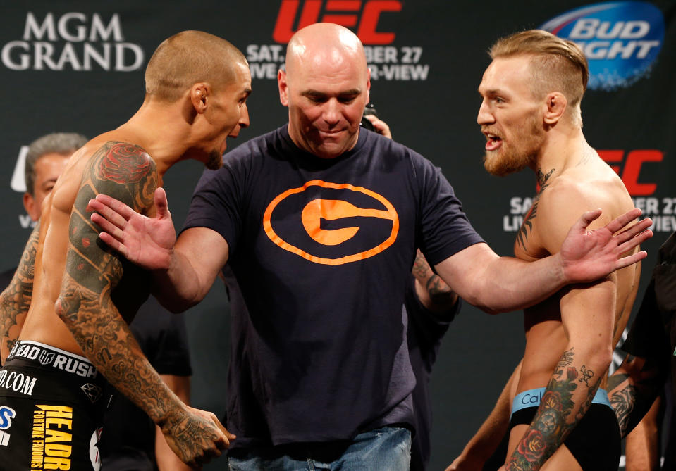 Dustin Poirier and Conor McGregor yell at each other with Dana White in between holding them apart. 