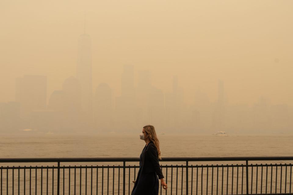 A heavy haze of smoke from the forest fires in Canada obscured the New York City Skyline from Jersey City on June 7, 2023. People walking along the water front stopped to take photos and were wearing masks due to the smoke in the air.