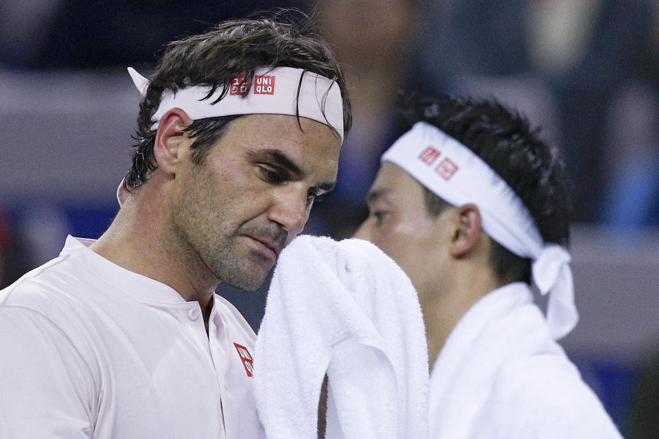 Roger Federer of Switzerland, left, and Kei Nishikori of Japan wipe faces during their men's singles quarterfinals match in the Shanghai Masters tennis tournament at Qizhong Forest Sports City Tennis Center in Shanghai, China, Friday, Oct. 12, 2018. (AP Photo/Andy Wong)