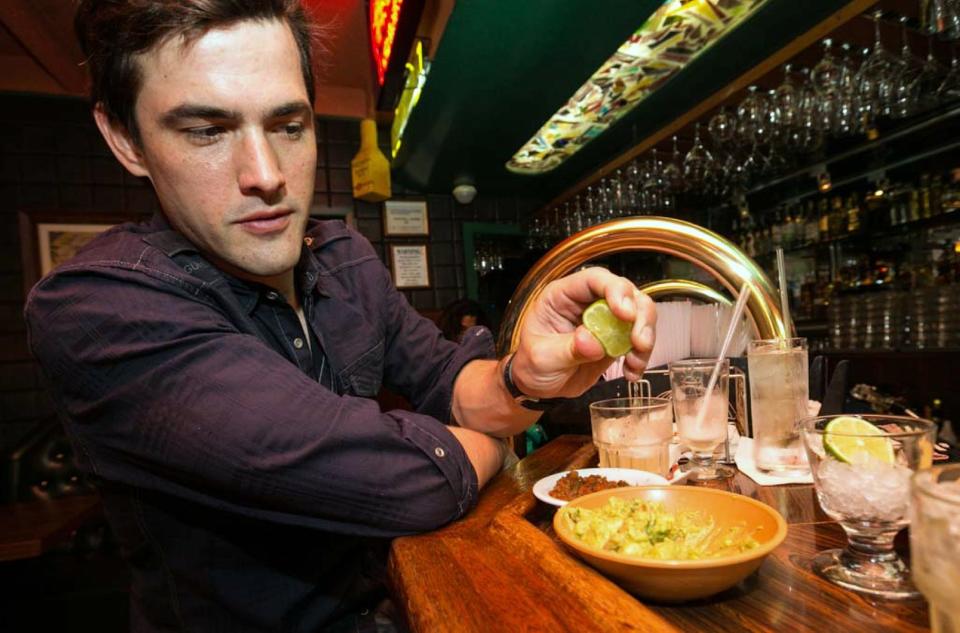 In this Monday, April 28, 2014 photo, Dana Stolzner squeezes lime juice to his guacamole, while drinking his own "Dana Margarita" a coconut based margarita cocktail at the bar of El Coyote, a Mexican restaurant in Los Angeles. Thousands of restaurateurs from coast to coast who have fallen victim to the Great Green Citrus Crisis of 2014. The price of a lime has skyrocketed in recent weeks, quadrupling or, in some areas, going even higher. (AP Photo)