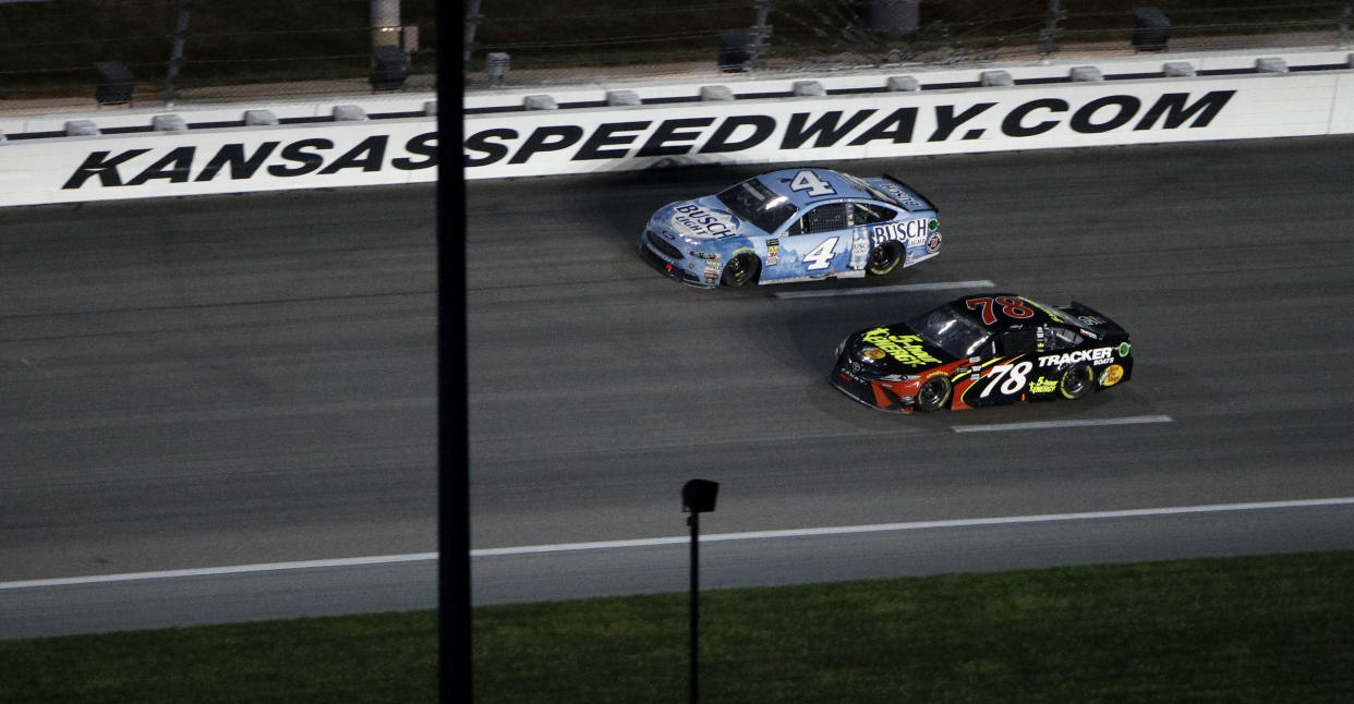 Kevin Harvick (4) passes Martin Truex Jr. (78) with a lap to go to win the NASCAR Cup Series auto race at Kansas Speedway on Saturday, May 12, 2018, in Kansas City, Kan. (AP Photo/Charlie Riedel)