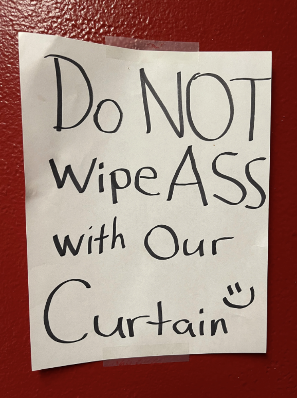 A hand-written sign taped to a wall reads, "Do NOT wipe ass with our curtain :)"