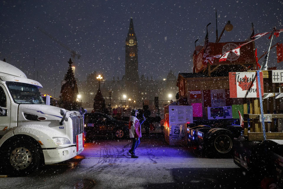 Protesters and supporters walk amongst trucks as they gather during a protest against COVID-19 measures that has grown into a broader anti-government protest that continues to occupy downtown Ottawa, Ontario, on Thursday, Feb. 17, 2022. (Cole Burston/The Canadian Press via AP)