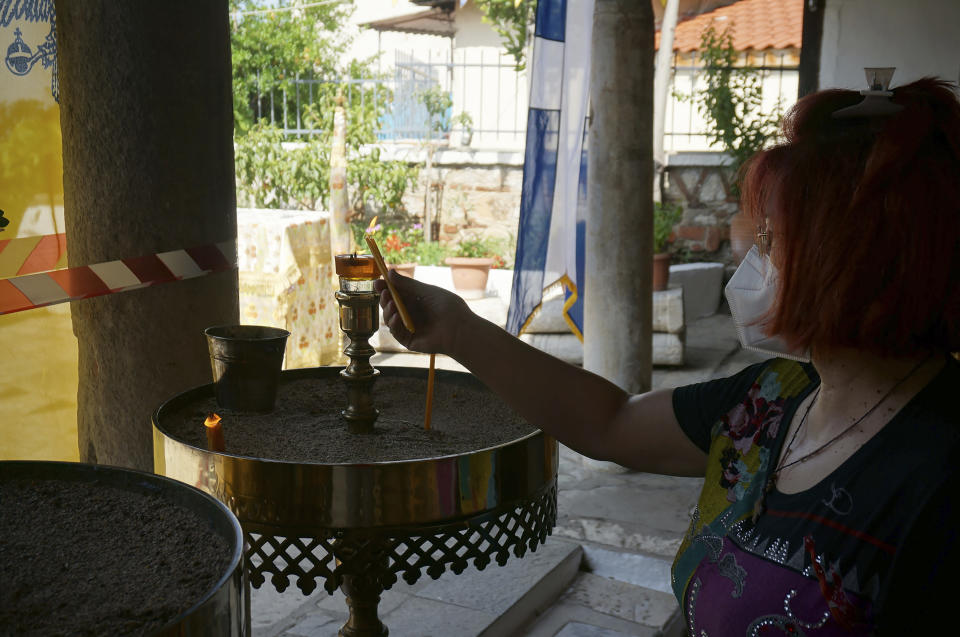 A visitor lights candles in the 5th-century church of Osios David on Saturday, June 25, 2022, in Thessaloniki, Greece. The small Orthodox Christian church preserves a 1,600-year-old Byzantine golden mosaic and medieval frescoes, making it a mandatory stop on a visit to Thessaloniki's many religious monuments. (AP Photo/Giovanna Dell'Orto)