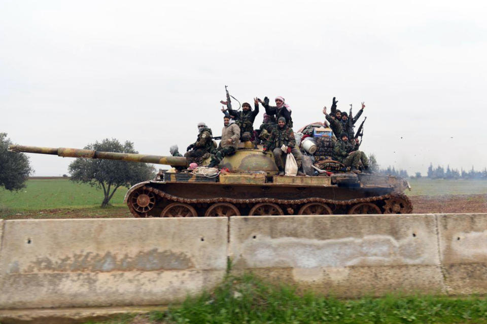 In this photo released Wednesday, Feb. 12, 2020, by the Syrian official news agency SANA, Syrian government soldiers on a tank hold up their rifles and flash victory signs, as they patrol the highway that links the capital Damascus with the northern city of Aleppo, Syria. The M5 highway, recaptured by President Bashar Assad’s forces this week, is arguably the most coveted prize in Syria’s civil war. The strategic highway is vital for Syria’s economy as well as for moving troops. (SANA via AP)
