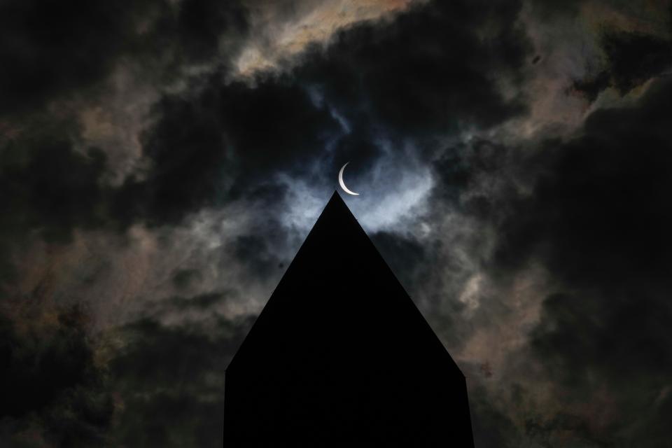 A partial eclipse is seen over the Washington Monument on Monday, April 8, 2024.