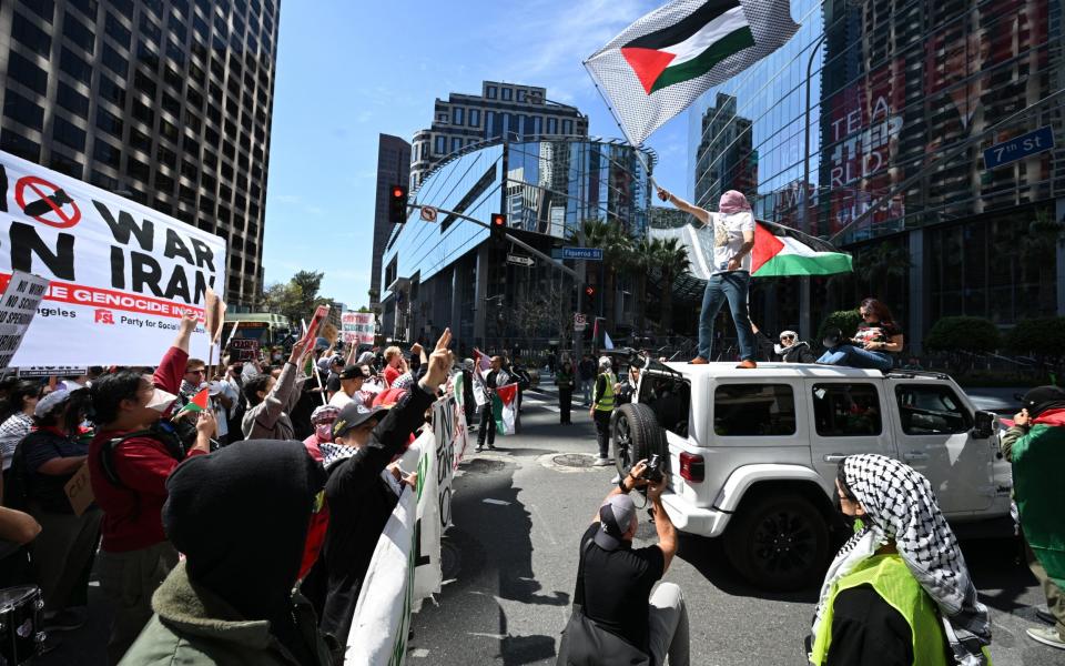 Demonstrators wave flags and temporarily block and intersection in downtown Los Angeles during a 