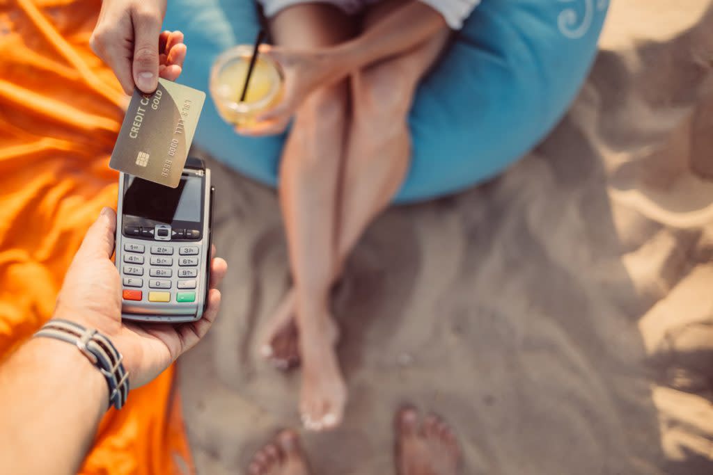 A woman uses a credit card for a drink on the beach. 